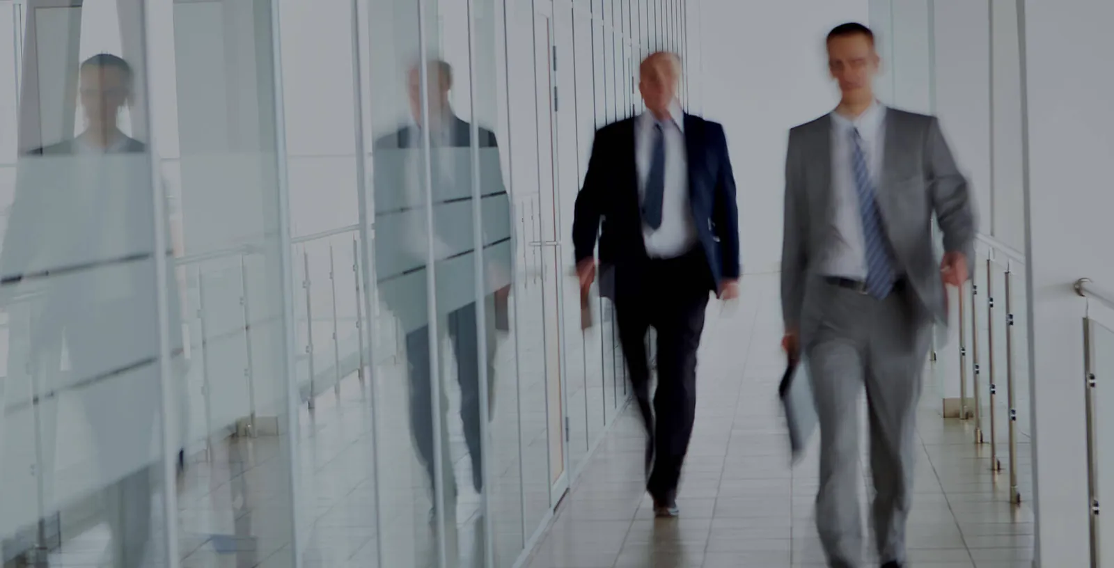 Business people walking along a glass-walled corridor.